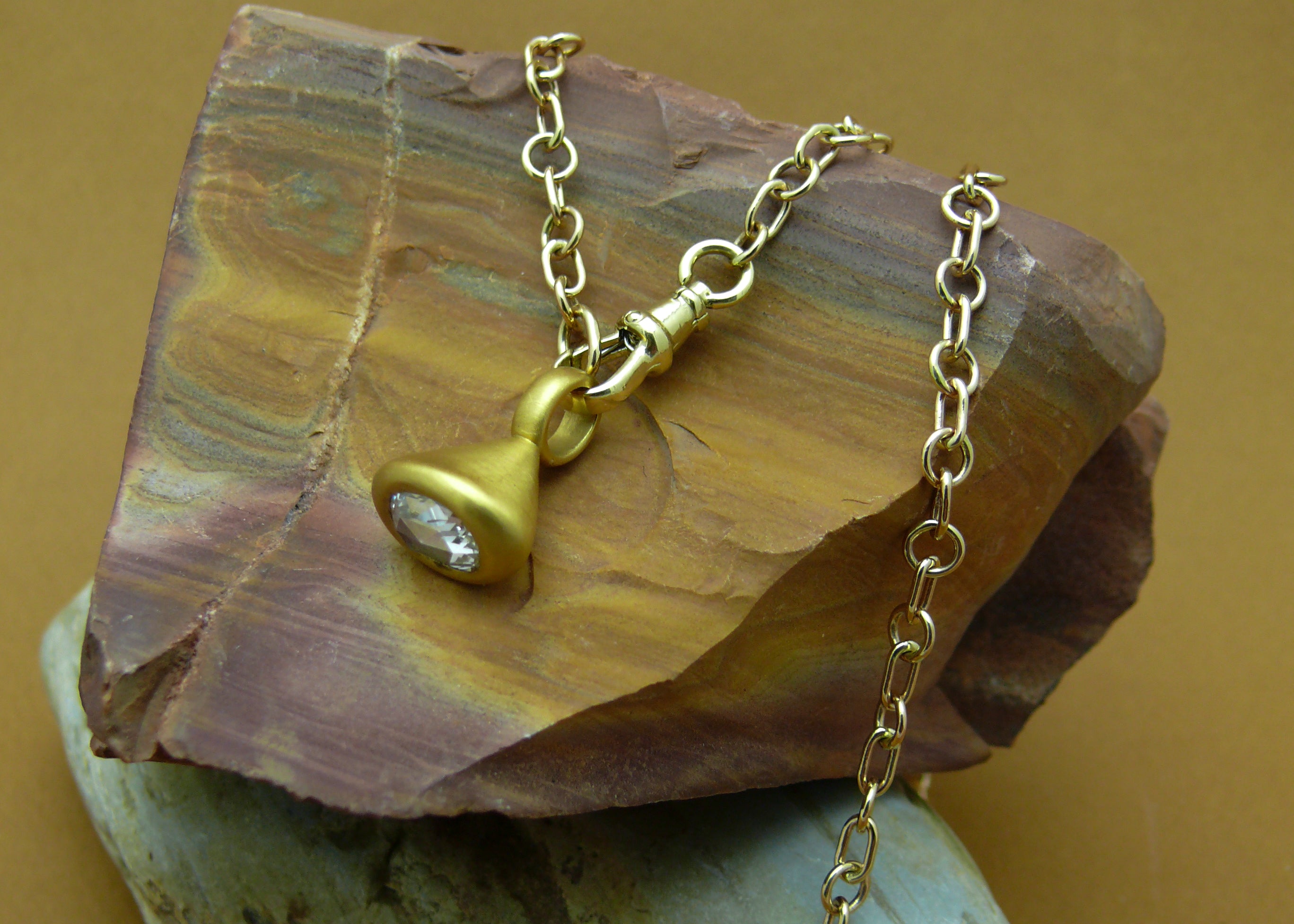 Gold-Fairmined-Rhythm-Chain-on rock with brown background