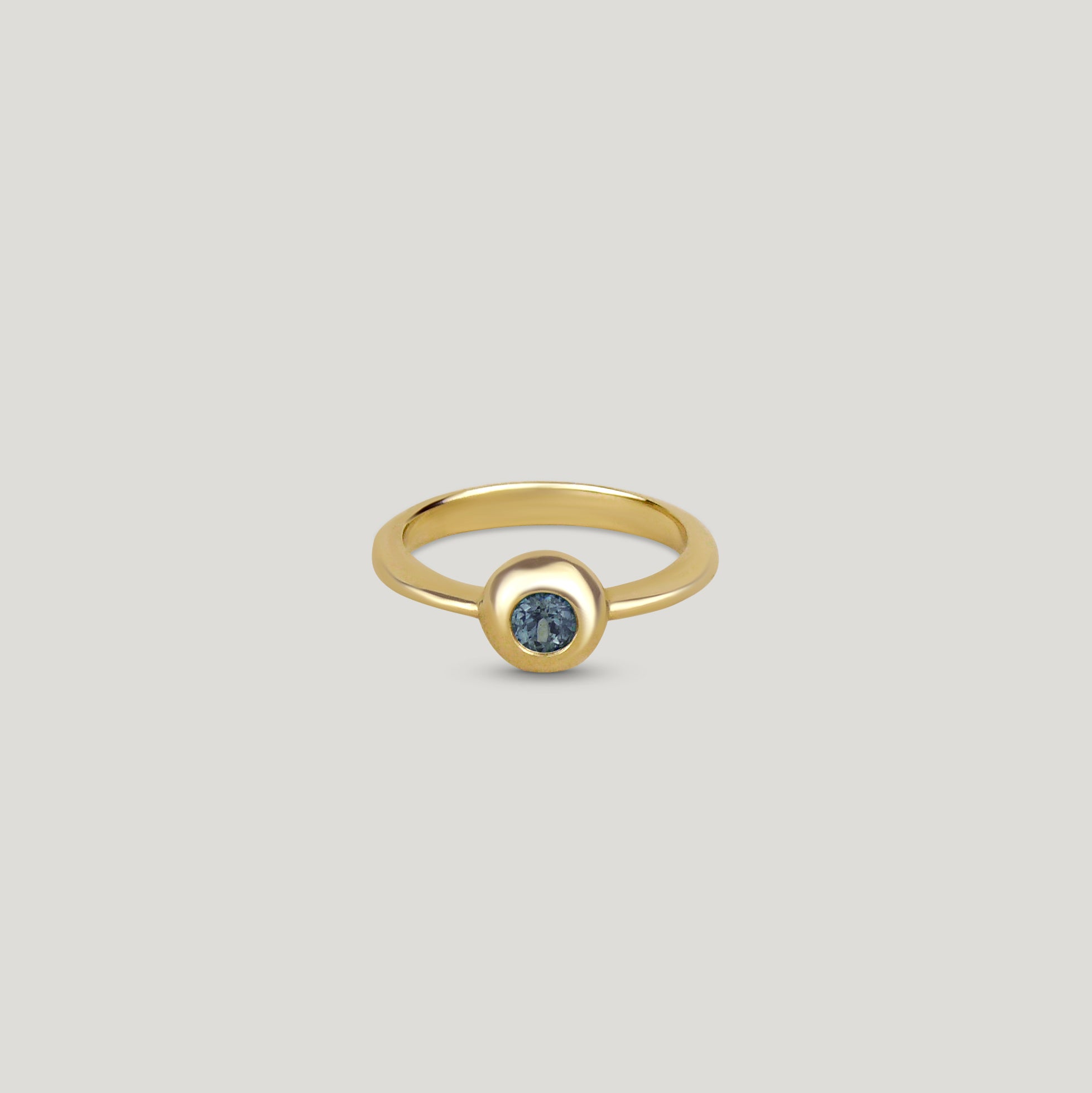 Yellow gold teal sapphire foundation solitaire ring on a neutral background