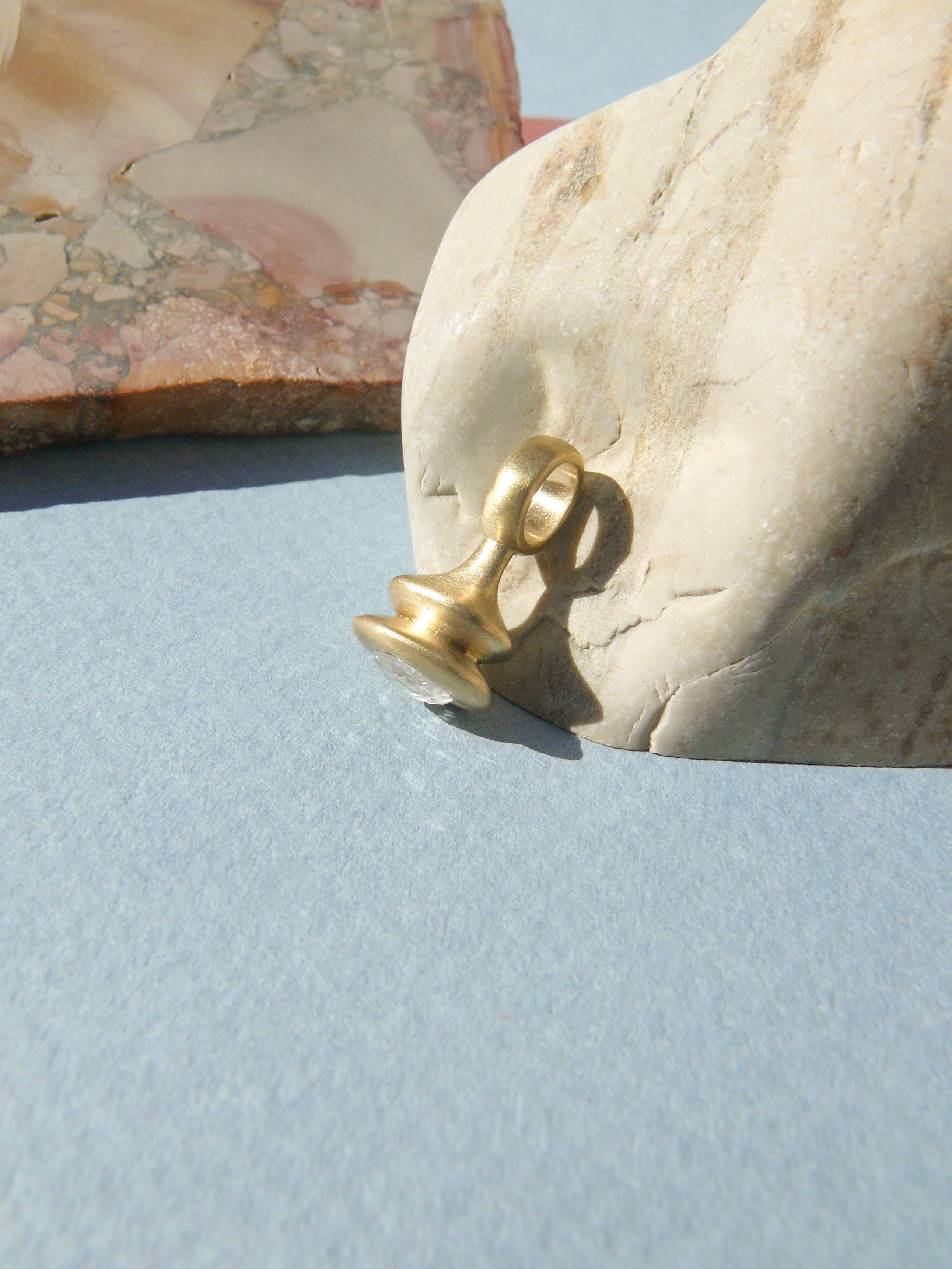 oval rose cut diamond pendulum charm no. 9 on rough rock background