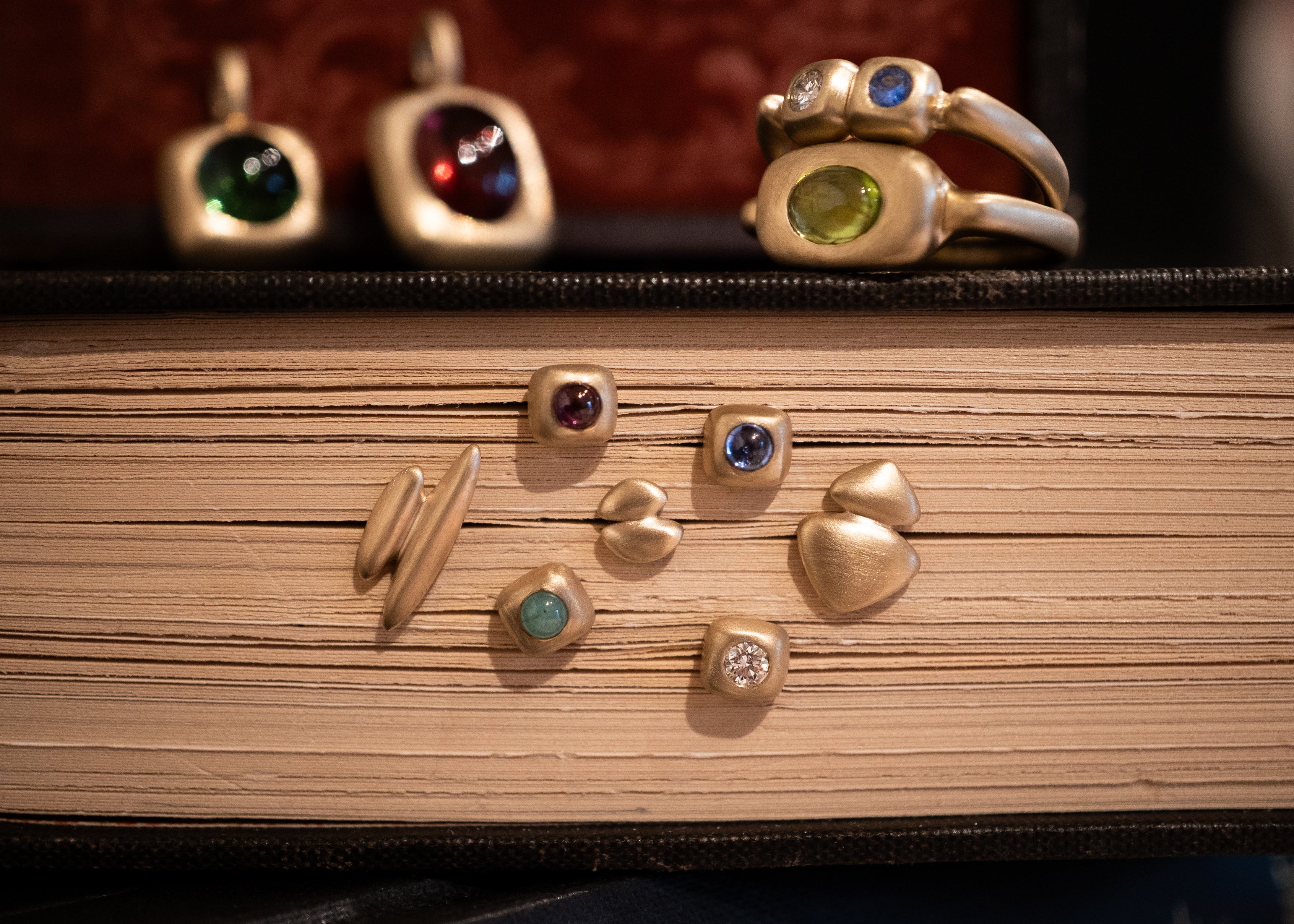 Trove Collection of gold jewelry with gemstones on a book surface