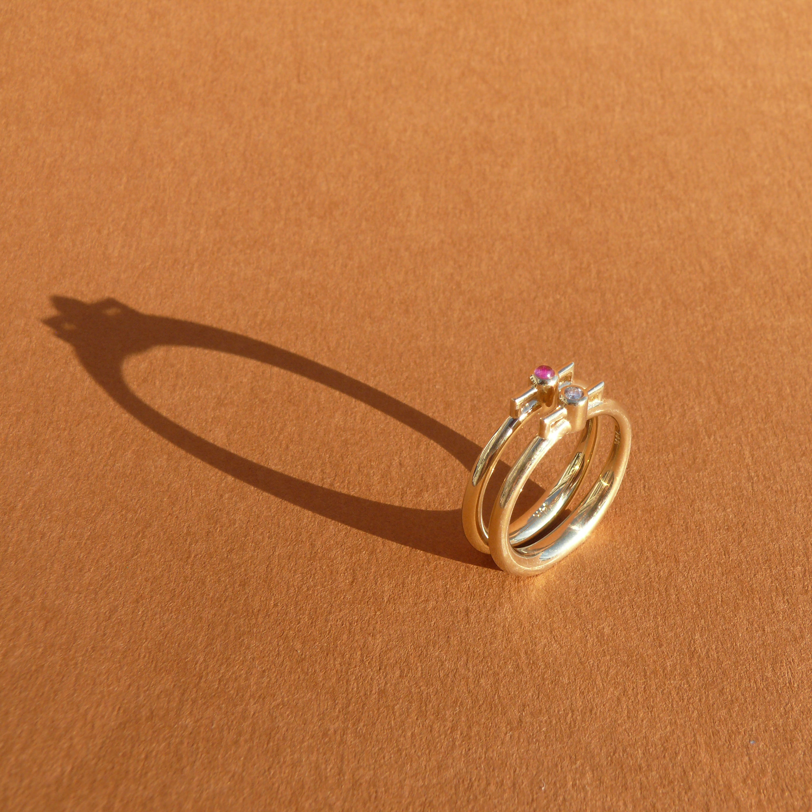 2mm Vietnamese ruby bezel set atop a 14k recycled yellow gold ring band with a silhouette of a vessel with square handles