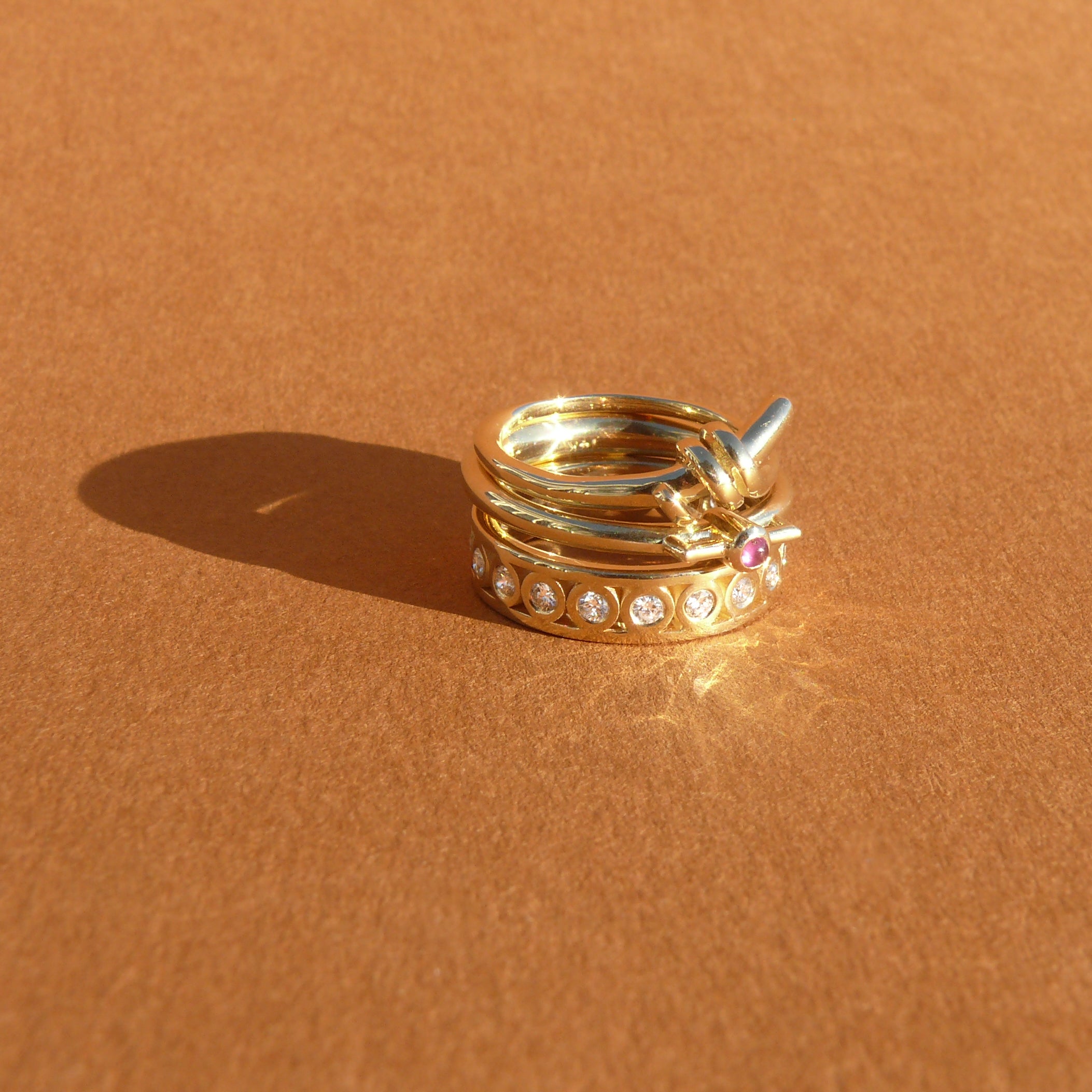 2mm Vietnamese ruby bezel set atop a 14k recycled yellow gold ring band with a silhouette of a vessel with square handles