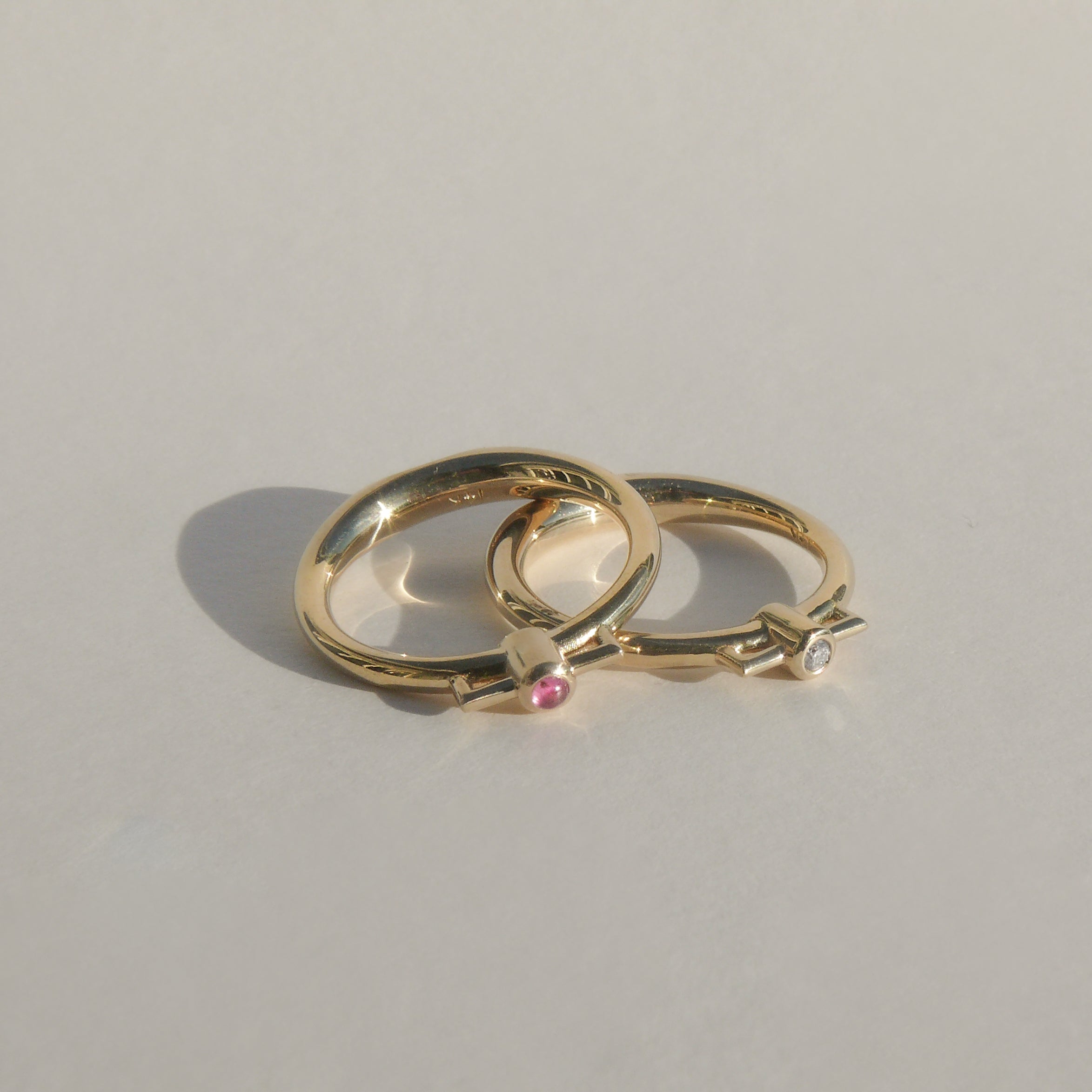 2mm recycled white diamond bezel set atop a 14k recycled yellow gold ring band with a silhouette of a vessel with square handles