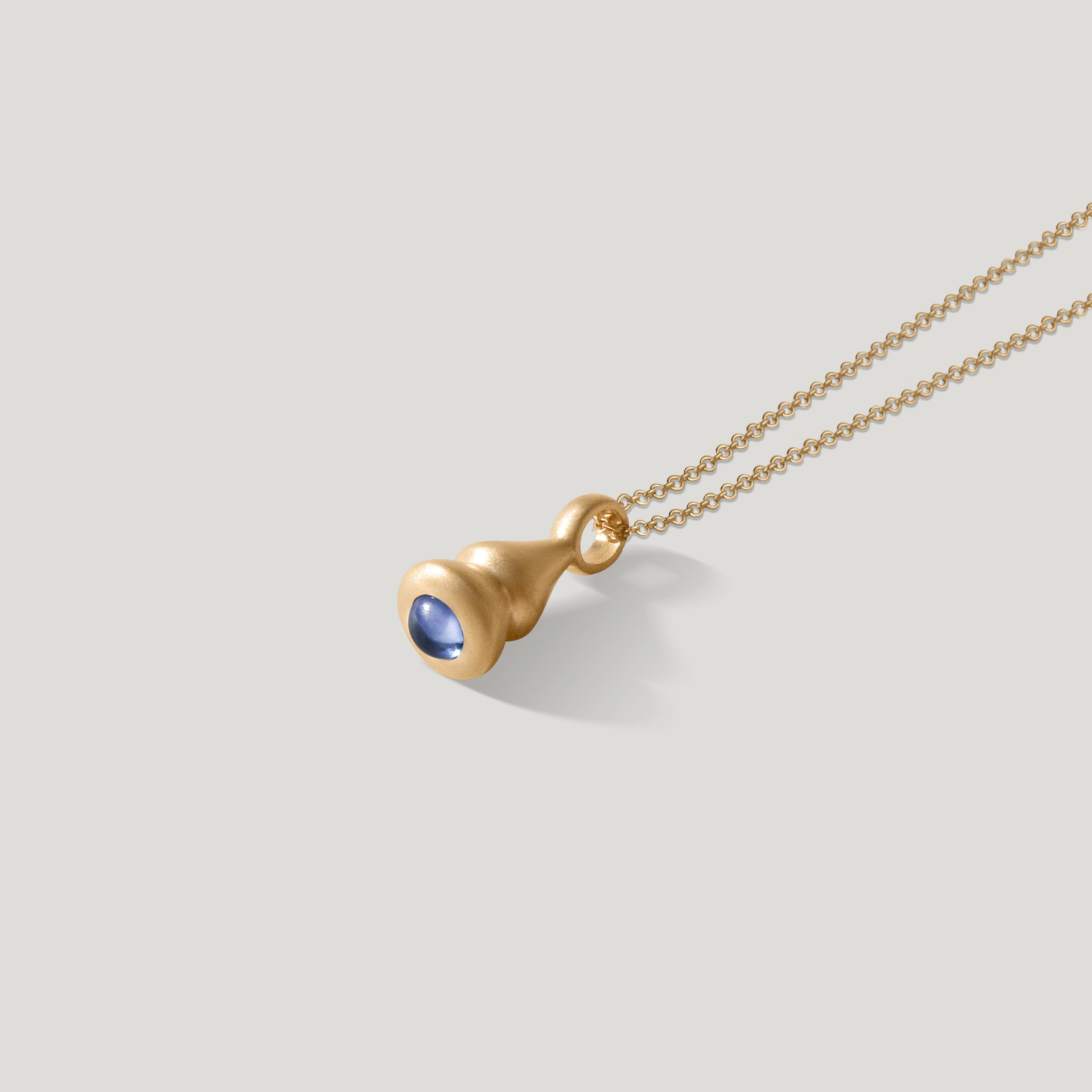 gold pendulum charm with blue sapphire on 1.5mm cable chain on grey background
