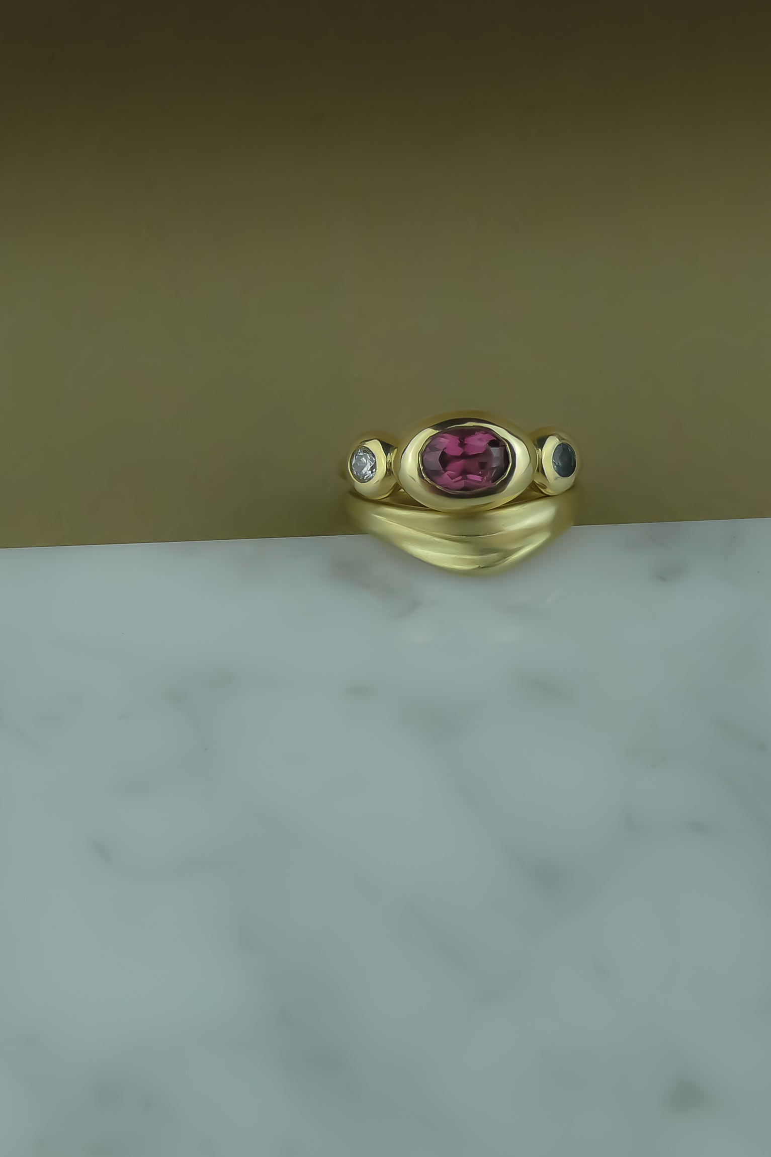 Foundation Trio Ring with garnet, teal sapphire, and diamond bezel set on a half round gold band and paired with a curved wedding band with organic texture