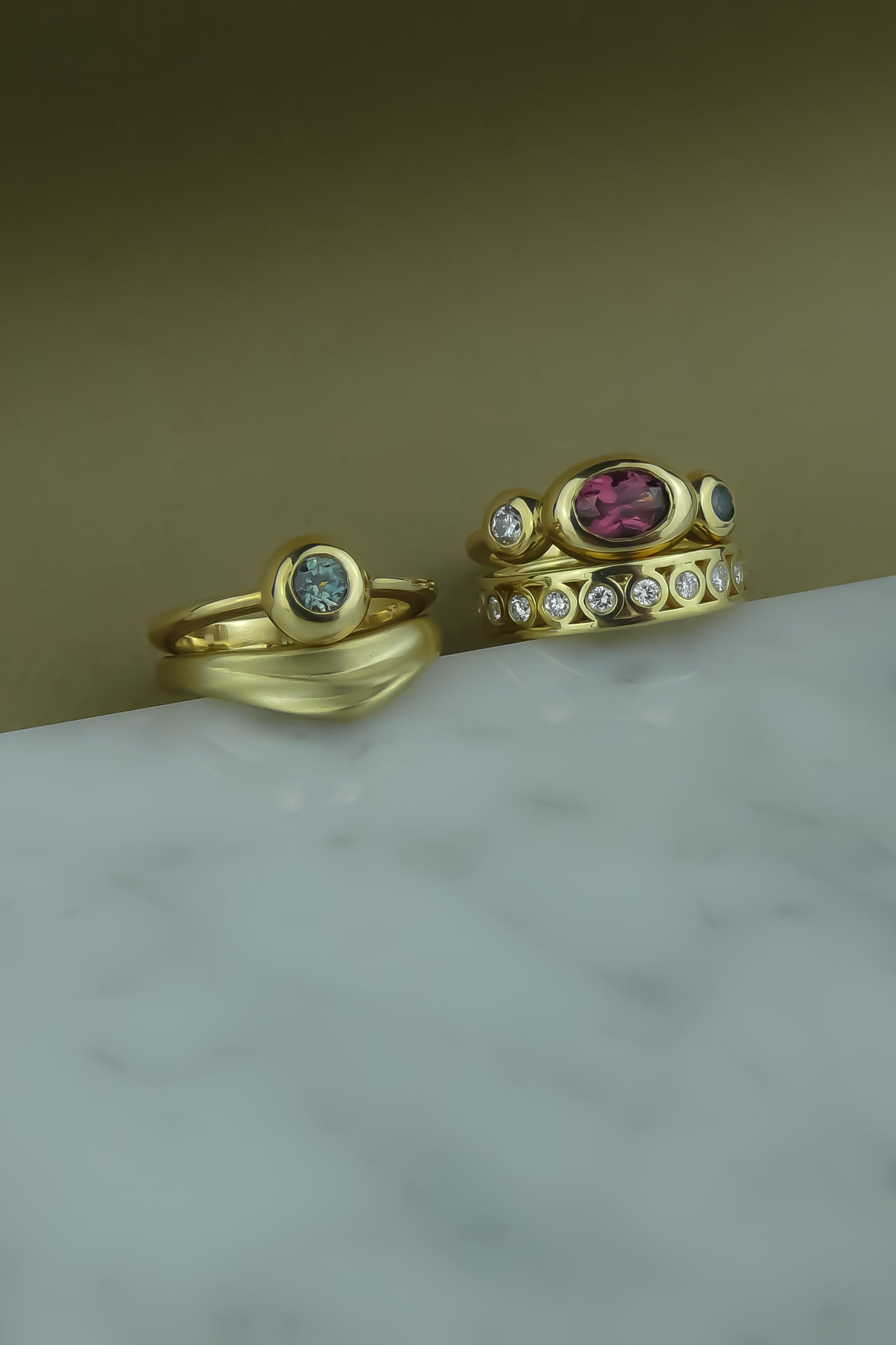 gold and teal sapphire foundation solitaire ring paired with a gold curved wedding band with organic texture