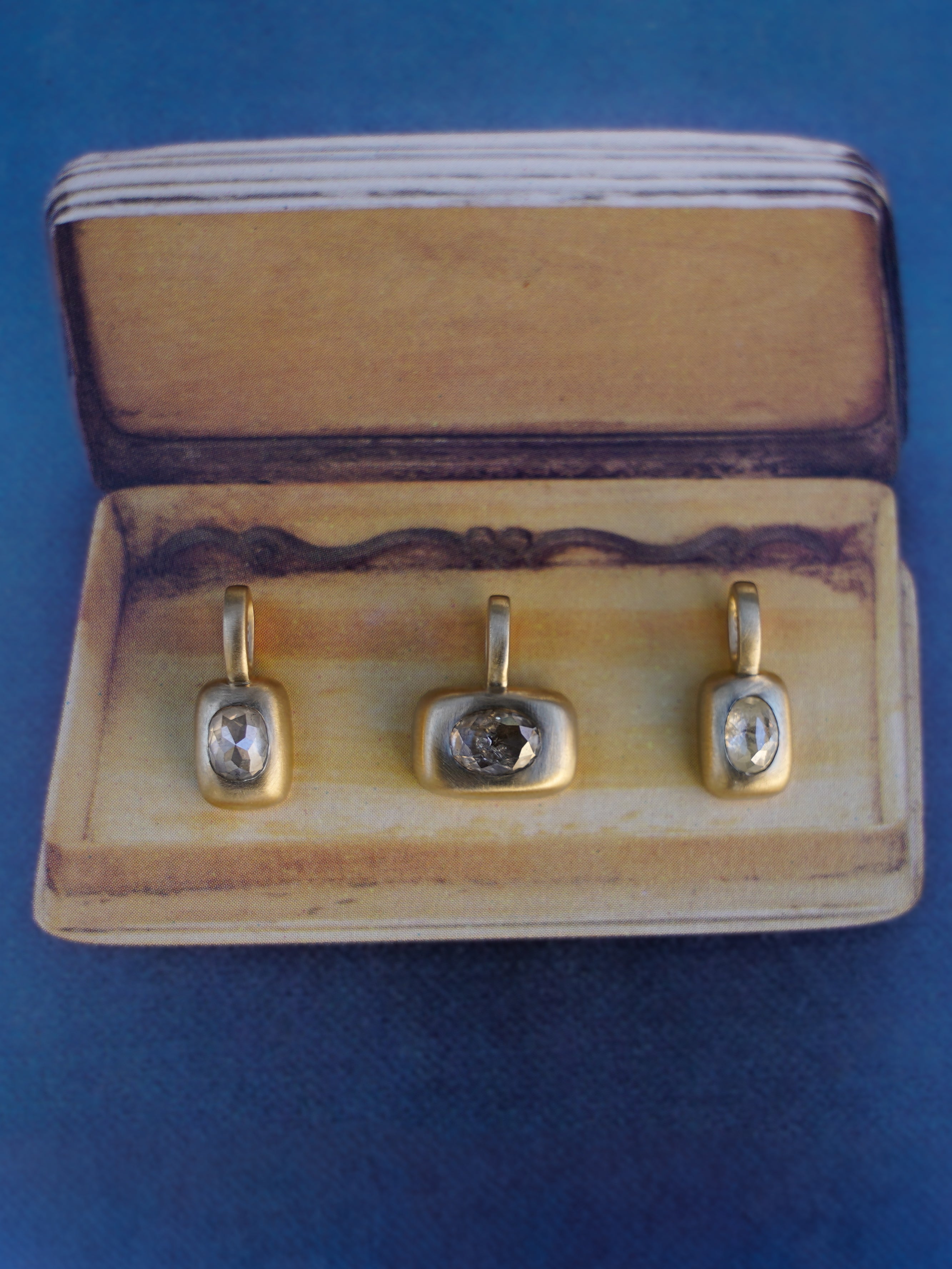 gold rose cut diamond trove charms on box with blue background