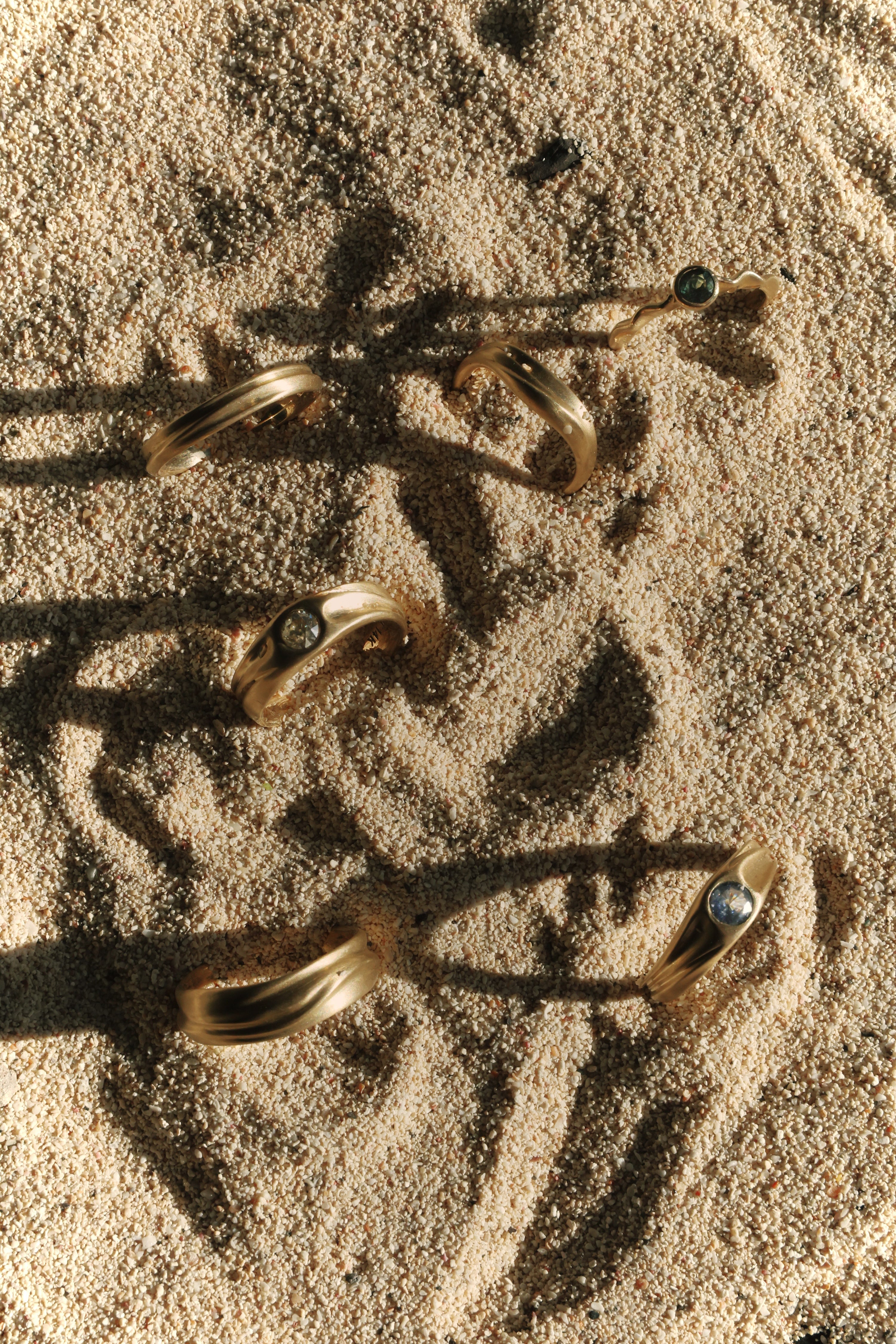 Dune Engagement and Wedding Rings on a sandy surface