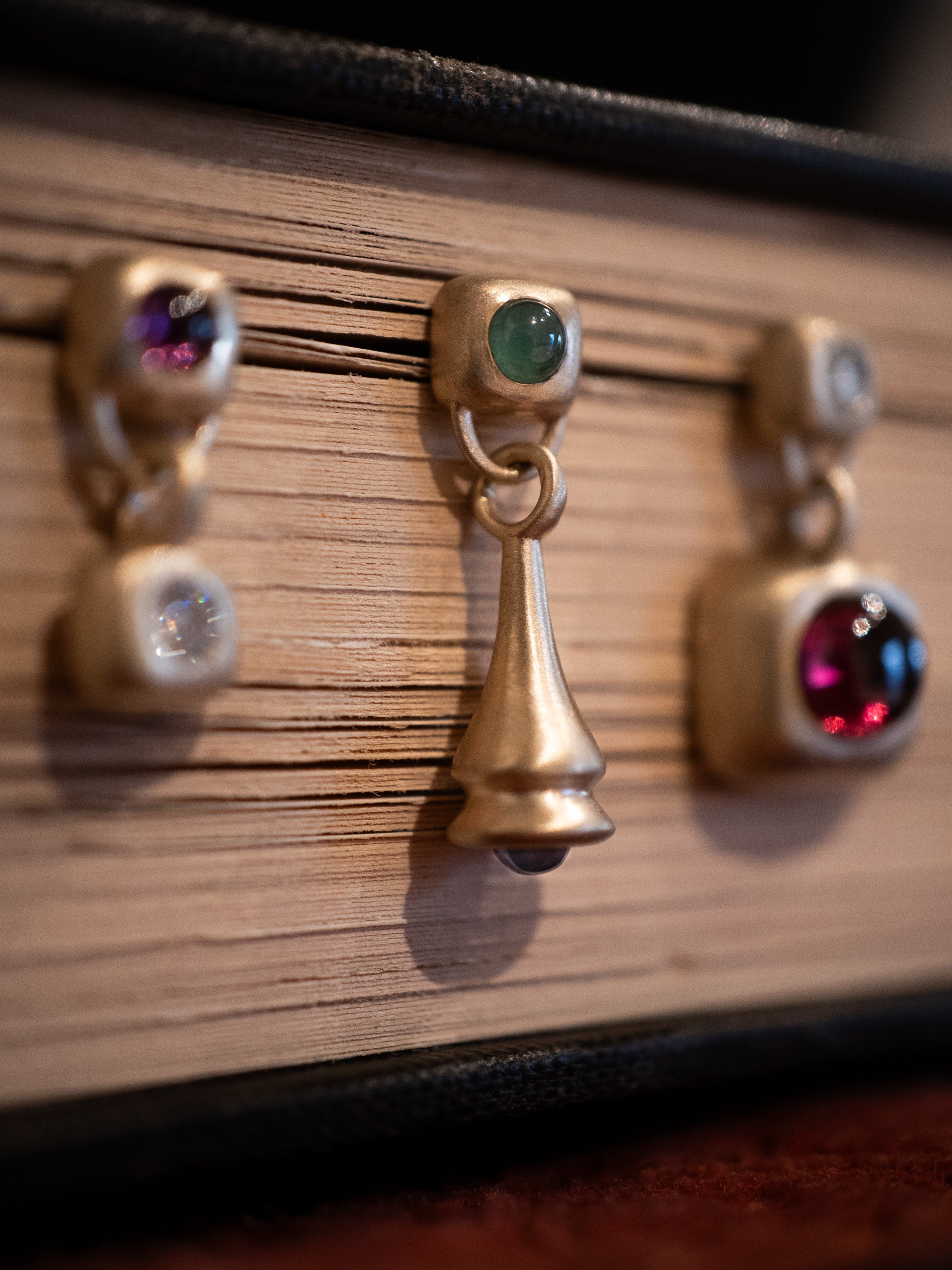 Three gold earrings with garnet, diamond, emeralds on a book surface