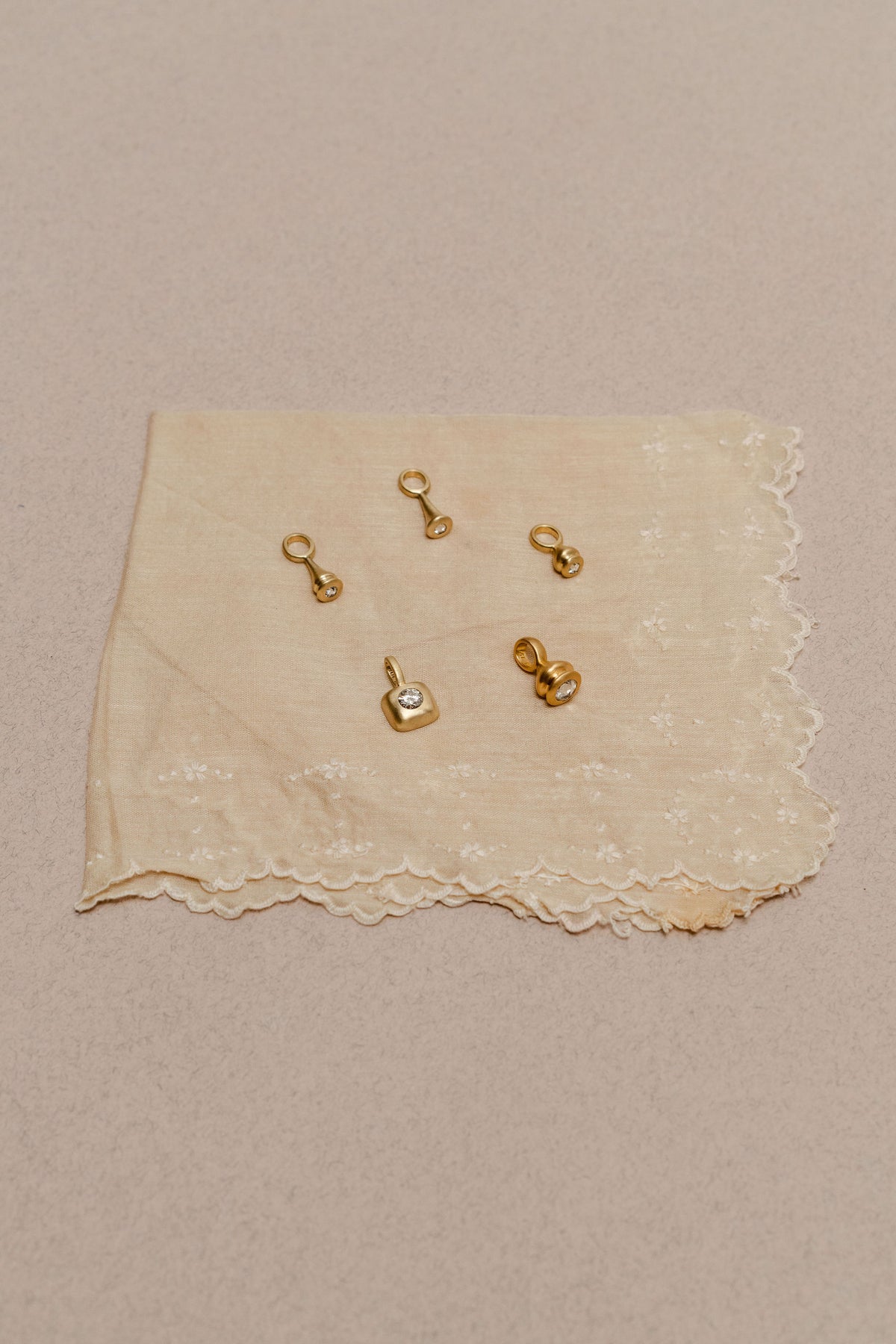 Gold and diamond charms on a beige vintage piece of fabric.