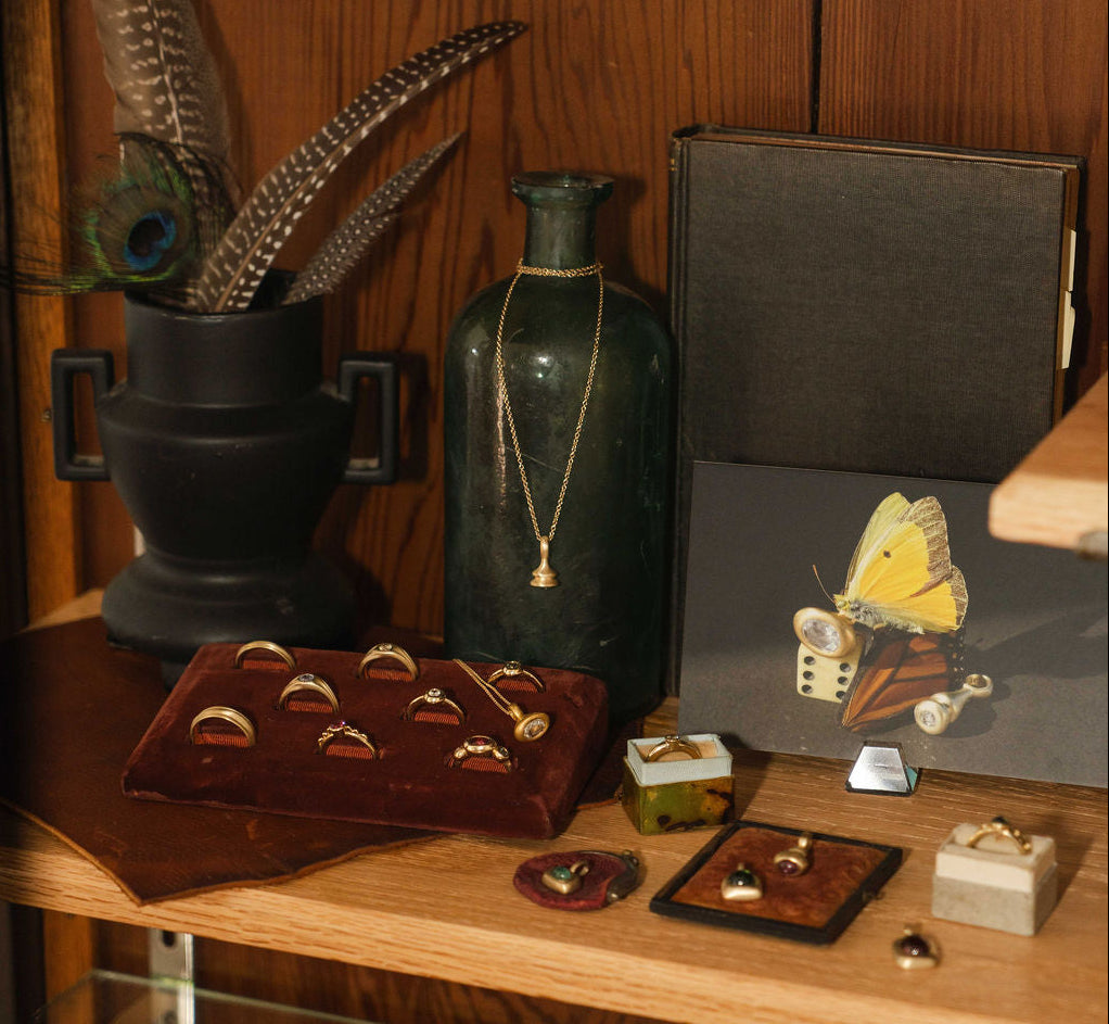 Made Line Jewelry studio with shelf holding books, gemstones, and gold jewelry.