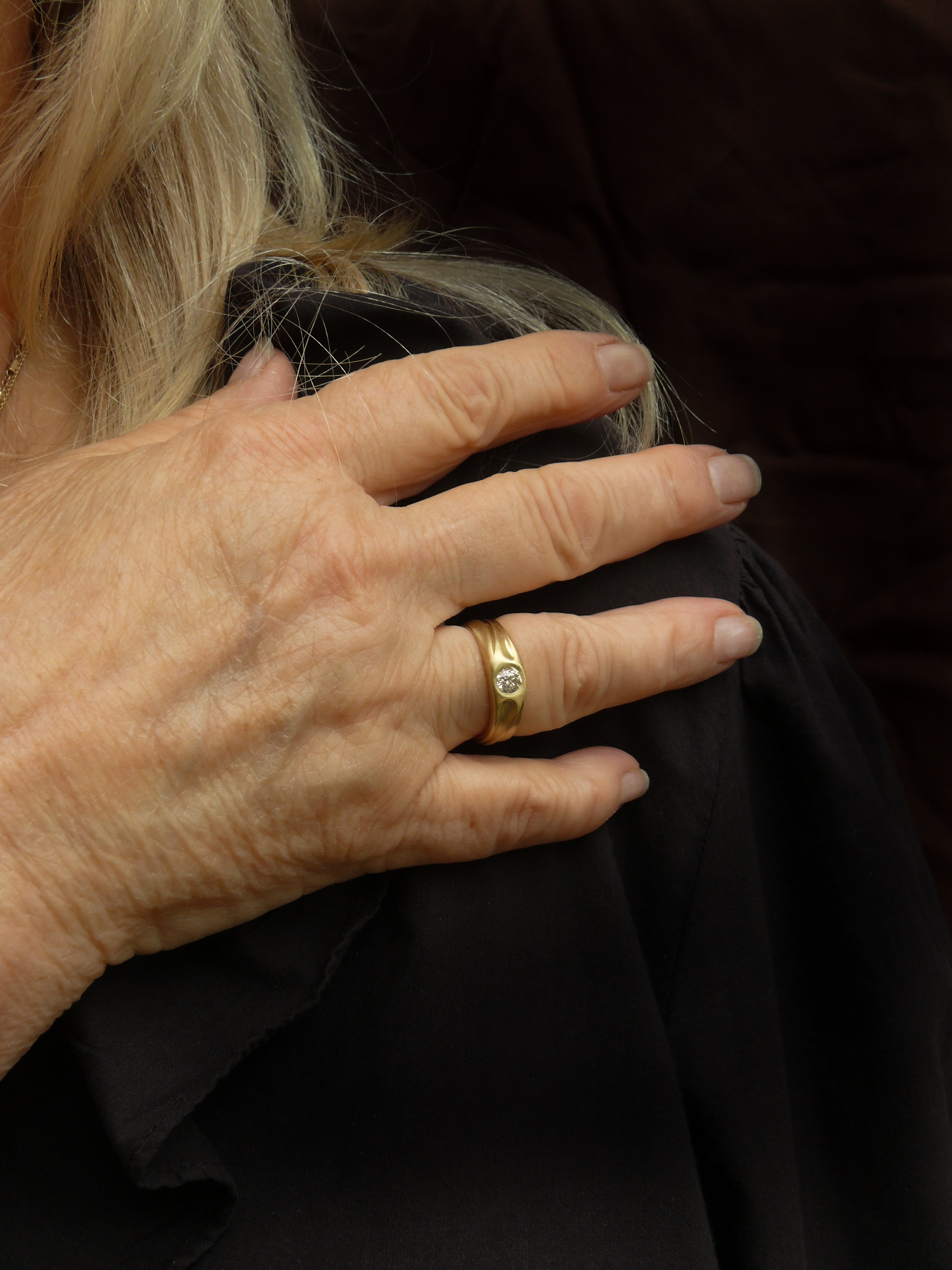 Hand with a old european cut diamond dune gold ring on a dark background