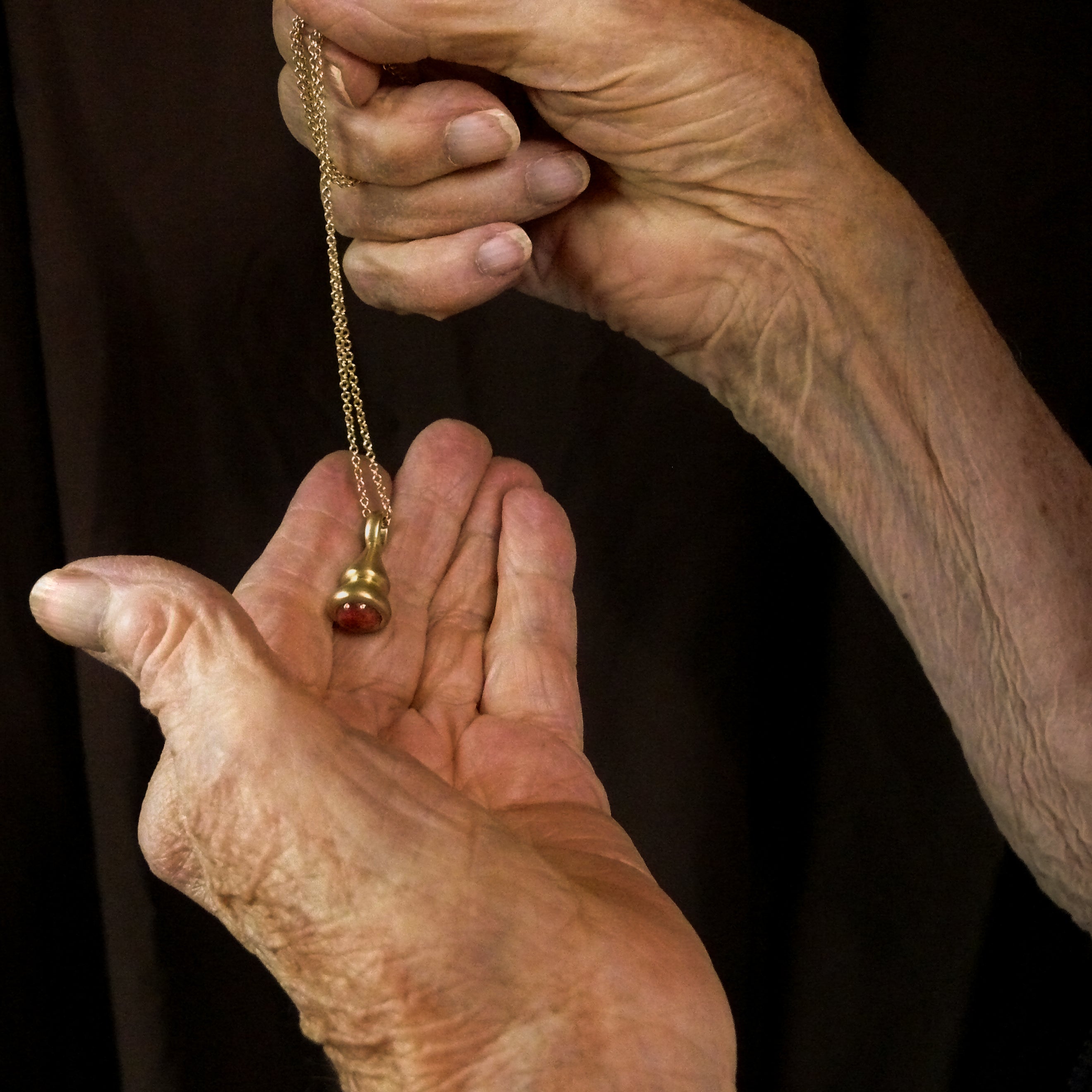 Gold tourmaline pendulum charm in grandma's hands