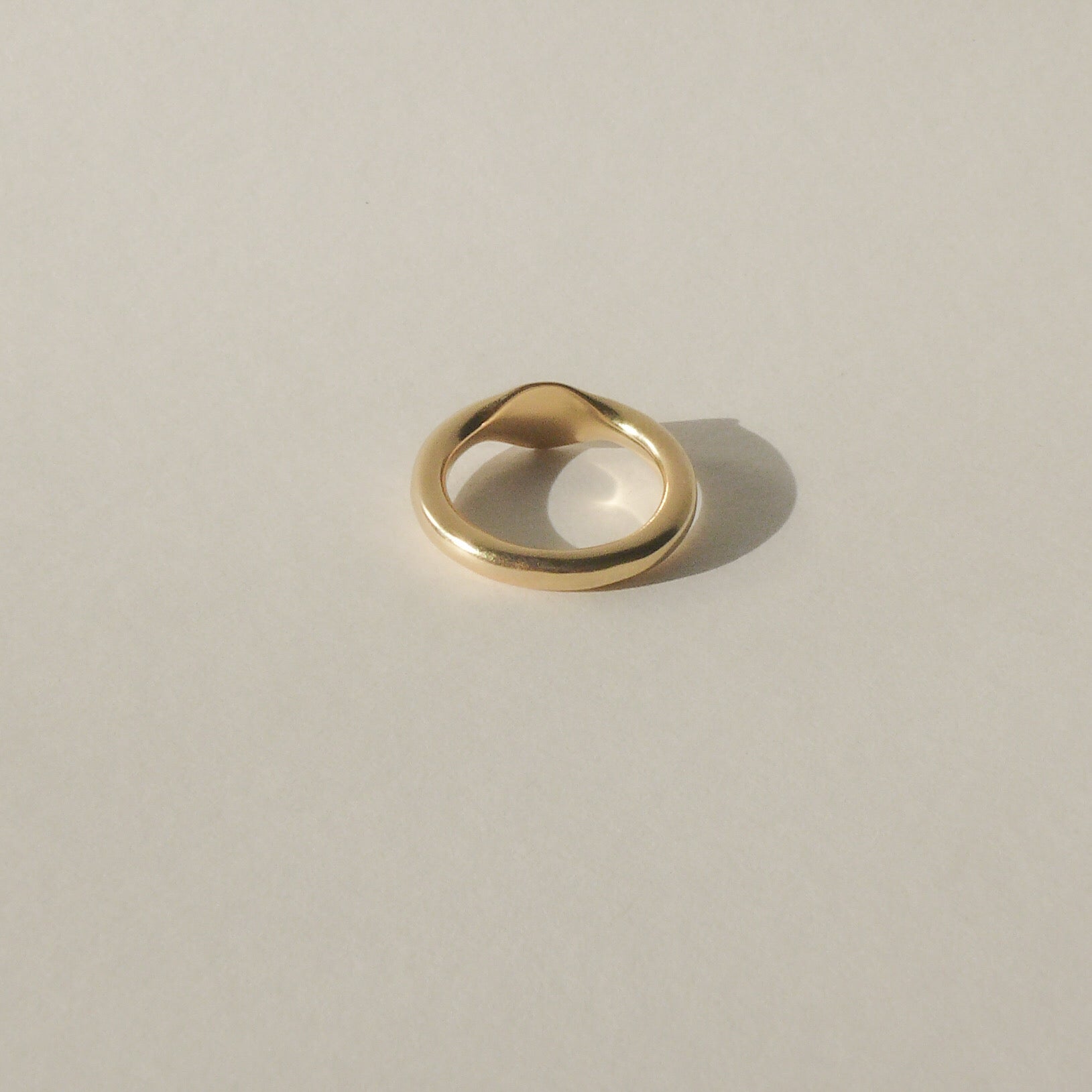 gold signet ring on white with shadow