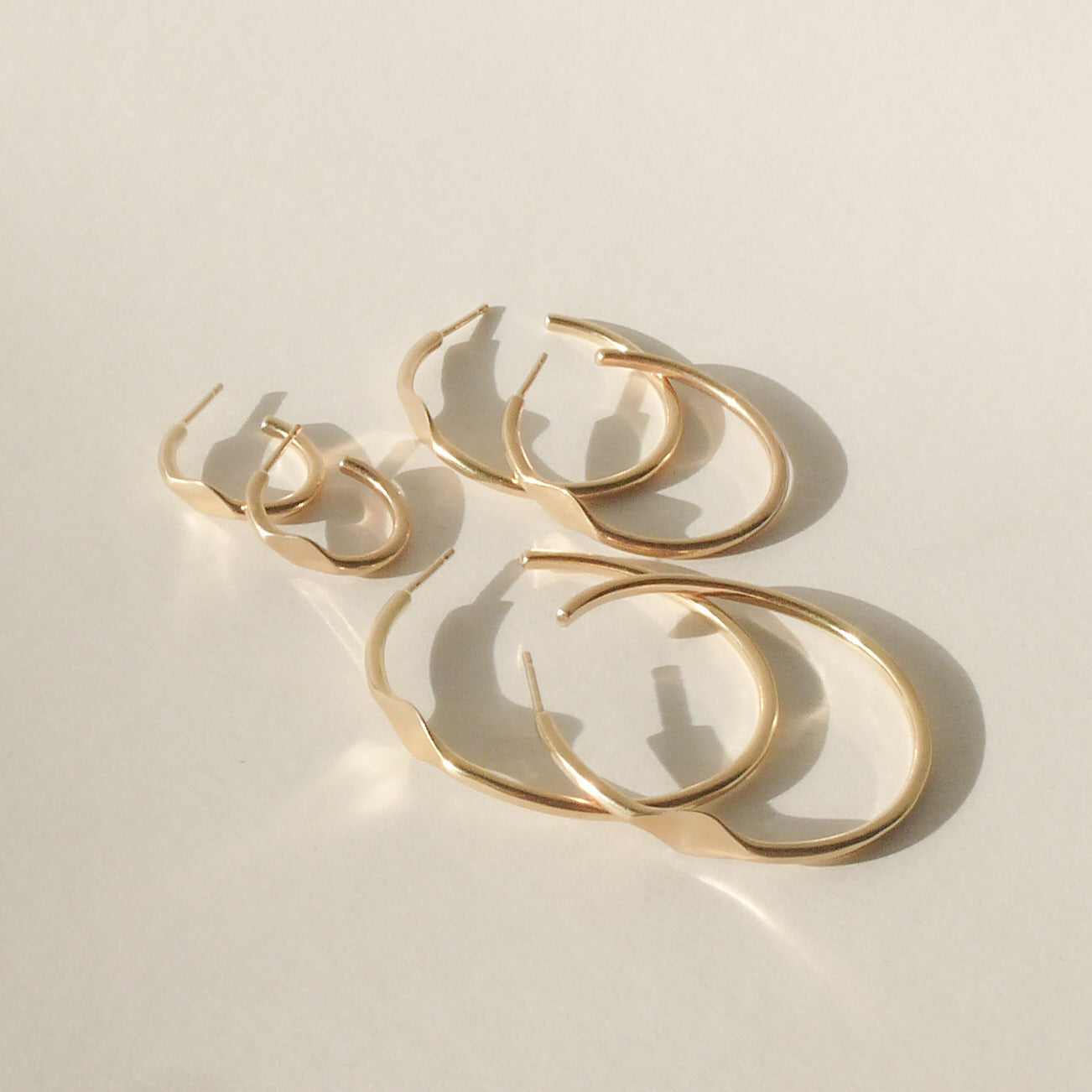 gold signet hoop earrings on white with shadow