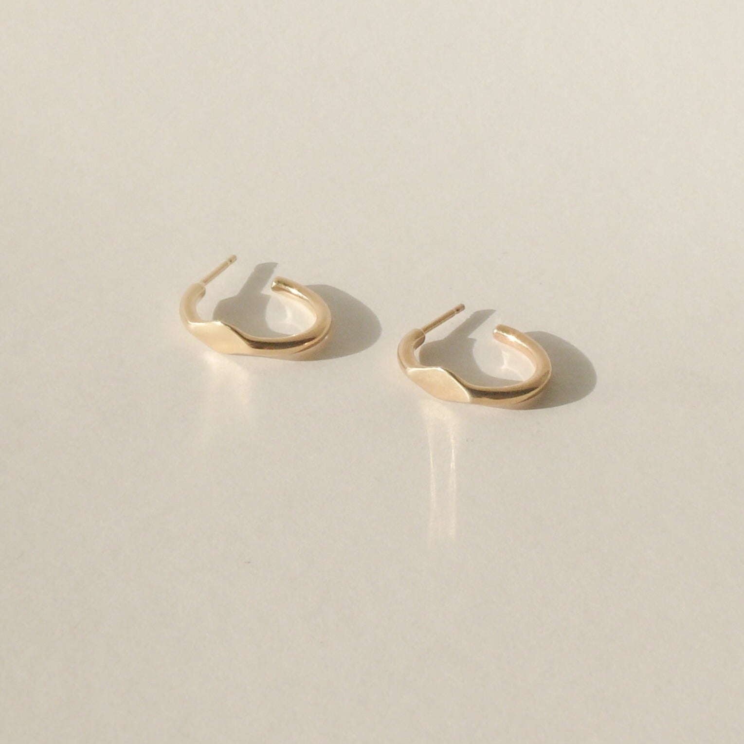 gold small signet hoop earrings on white with shadow