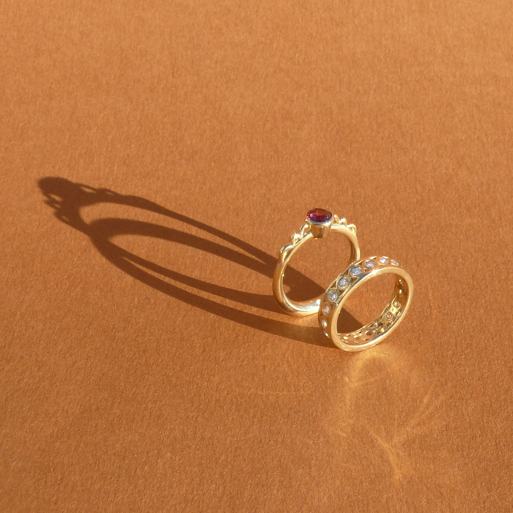 5mm fuchsia rhodolite garnet bezel set atop a 14k recycled yellow gold ring band with a silhouette of a vessel with round handles