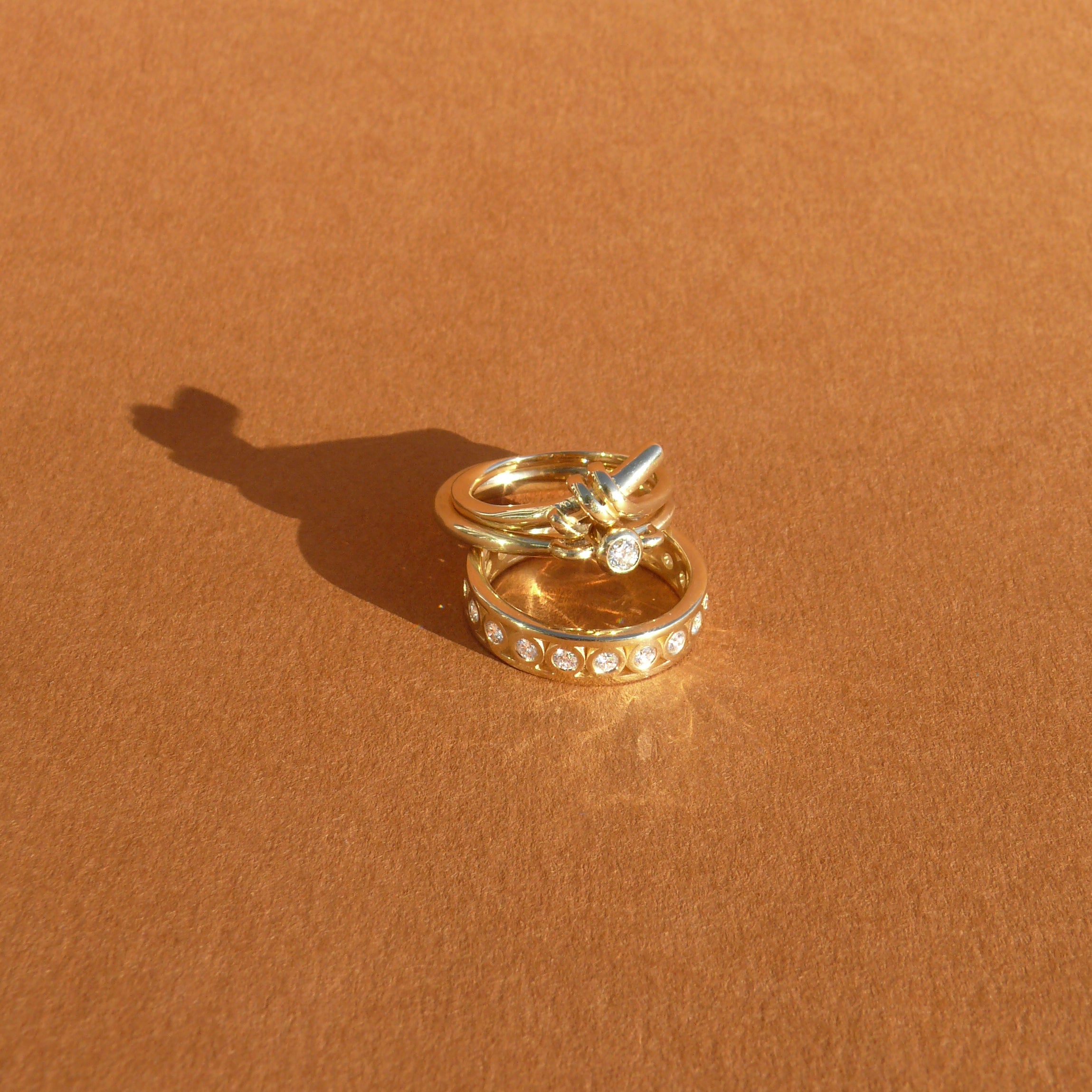 3mm recycled white diamond bezel set atop a 14k recycled yellow gold ring band with a silhouette of a vessel with round handles